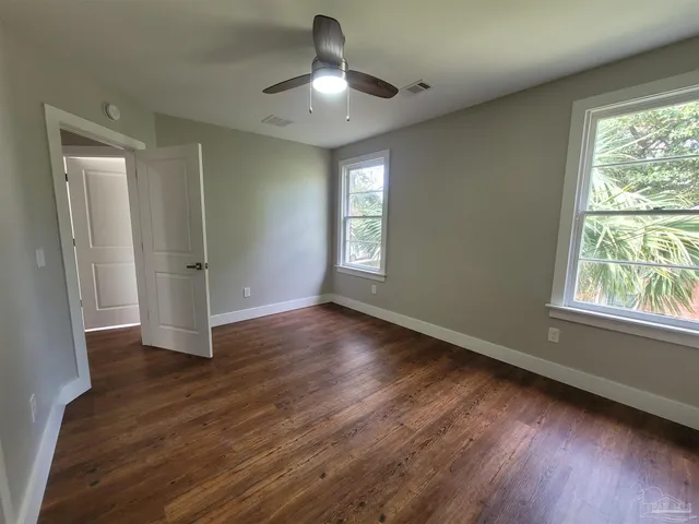 a view of empty room with wooden floor and fan