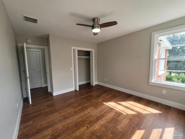 a view of empty room with wooden floor and fan