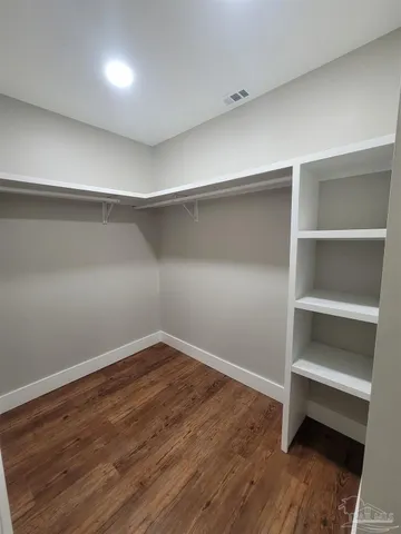 a view of an empty room with wooden floor and closet