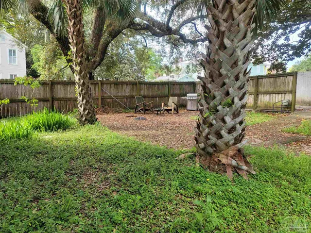 a view of a backyard with table and chairs and a large tree