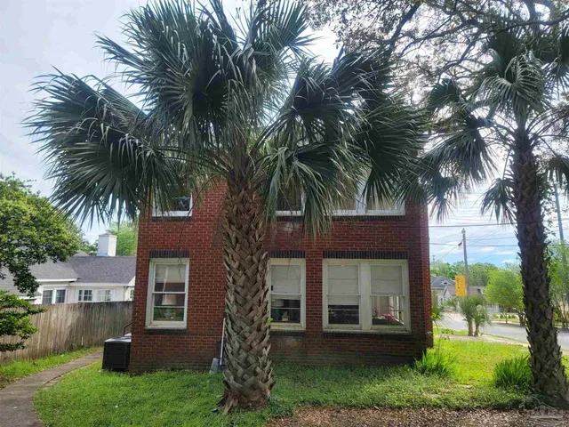 a view of a house with a yard and palm trees