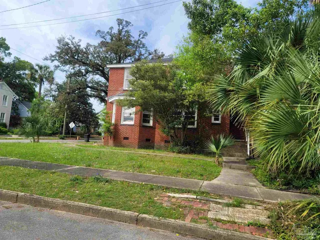 front view of a house with a yard and an trees