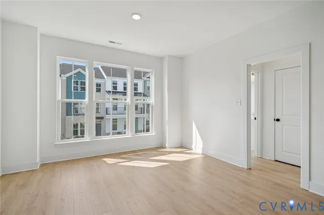 an empty room with wooden floor and windows