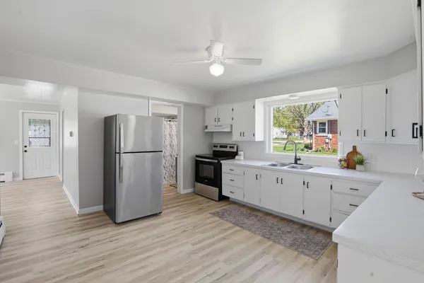 a kitchen with a refrigerator a sink dishwasher a stove and white cabinets with wooden floor
