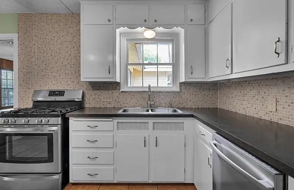 a kitchen with granite countertop white cabinets and a stove with a sink