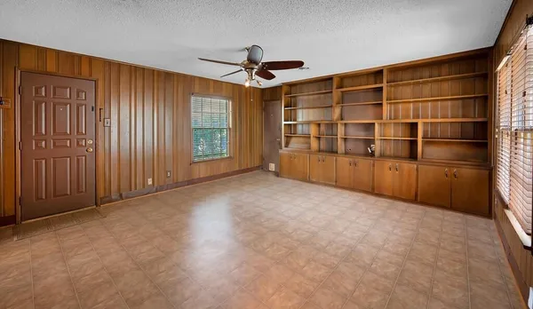 an empty room with windows and cabinet