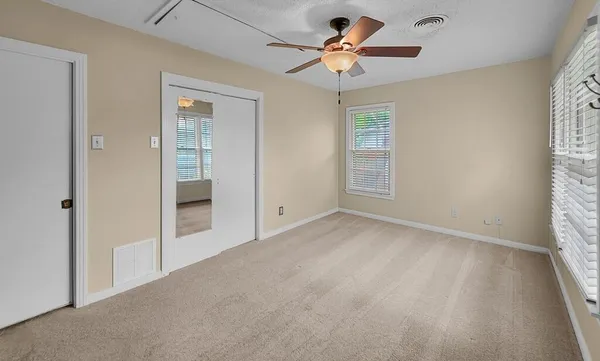 an empty room with windows and a ceiling fan