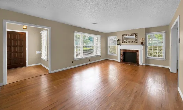 an empty room with wooden floor fireplace and windows