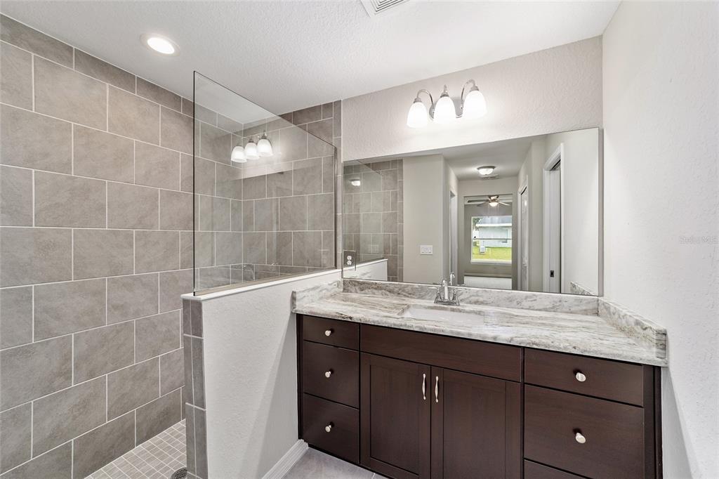 7866 North Manville Road Citrus Springs, FL 34434 - Photo 8 of 19 a bathroom with a granite countertop sink a large mirror and a shower
