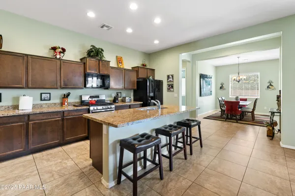 a kitchen with kitchen island granite countertop wooden cabinets a dining table and chairs