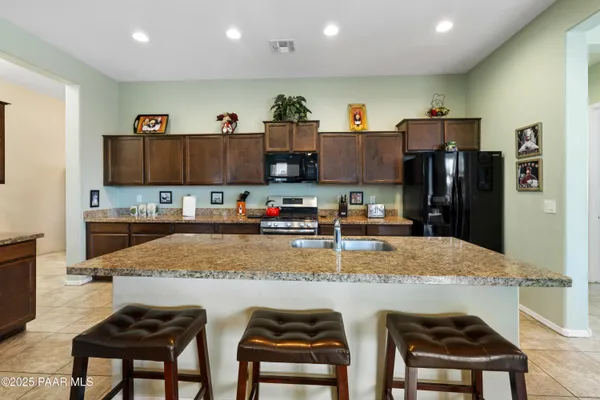 a kitchen with stainless steel appliances granite countertop a sink refrigerator and cabinets