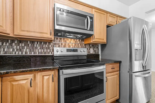 a kitchen with stainless steel appliances granite countertop a refrigerator and a stove top oven