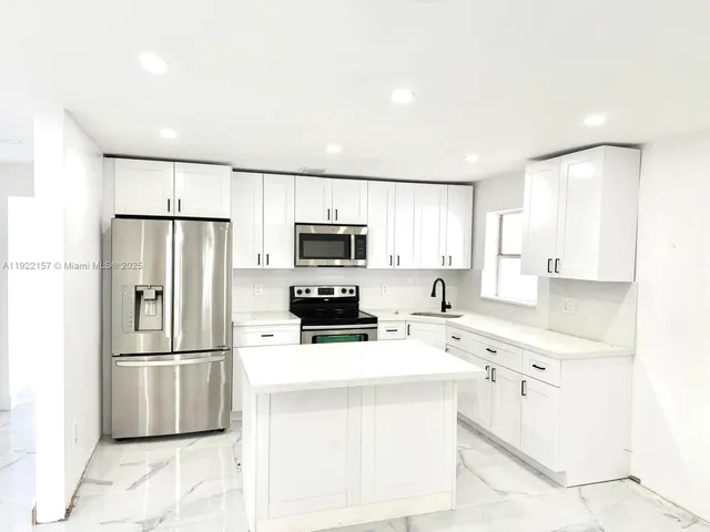 a kitchen with stainless steel appliances a refrigerator sink and microwave