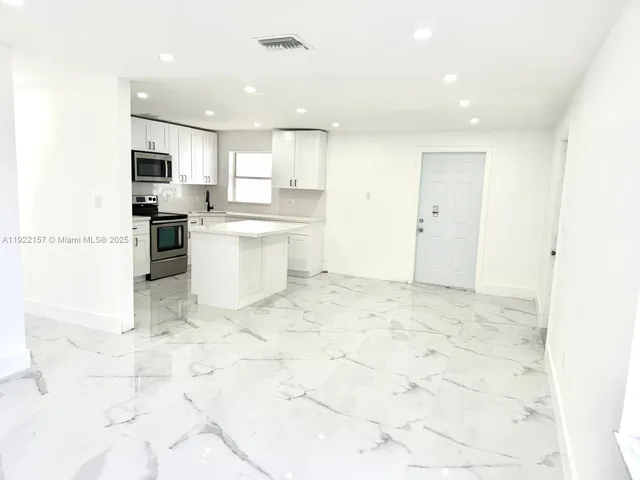 a large white kitchen with kitchen island a sink a stove a microwave and a refrigerator
