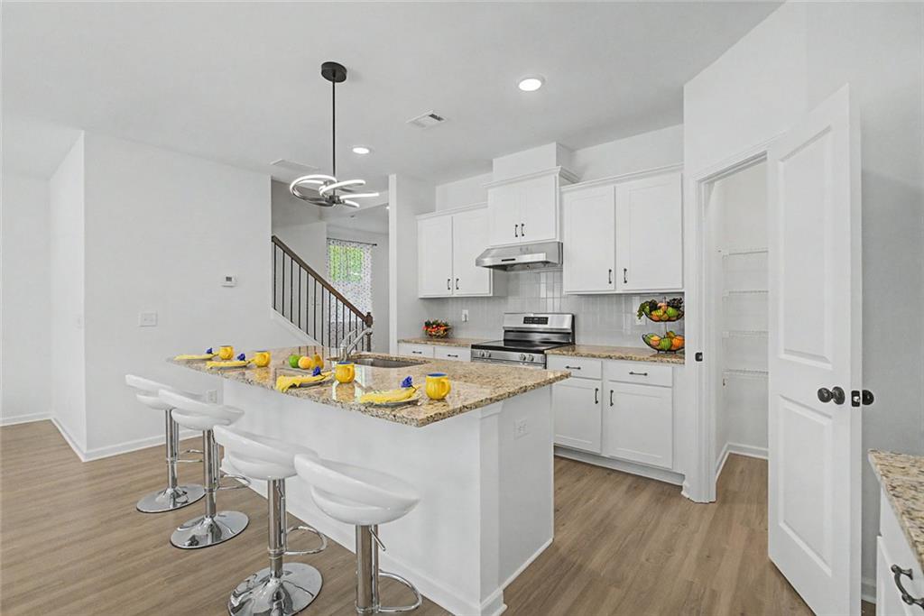 2310 Portrush Way Southeast Atlanta, GA 30339 - Photo 10 of 38 a kitchen with stainless steel appliances granite countertop a sink dishwasher a stove a dining table and chairs with wooden floor