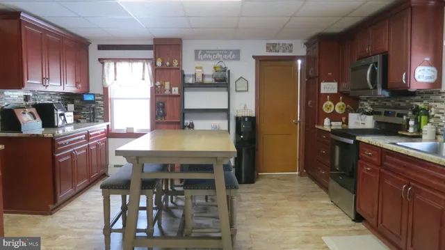 a kitchen with stainless steel appliances kitchen island granite countertop a refrigerator a stove and a wooden cabinets