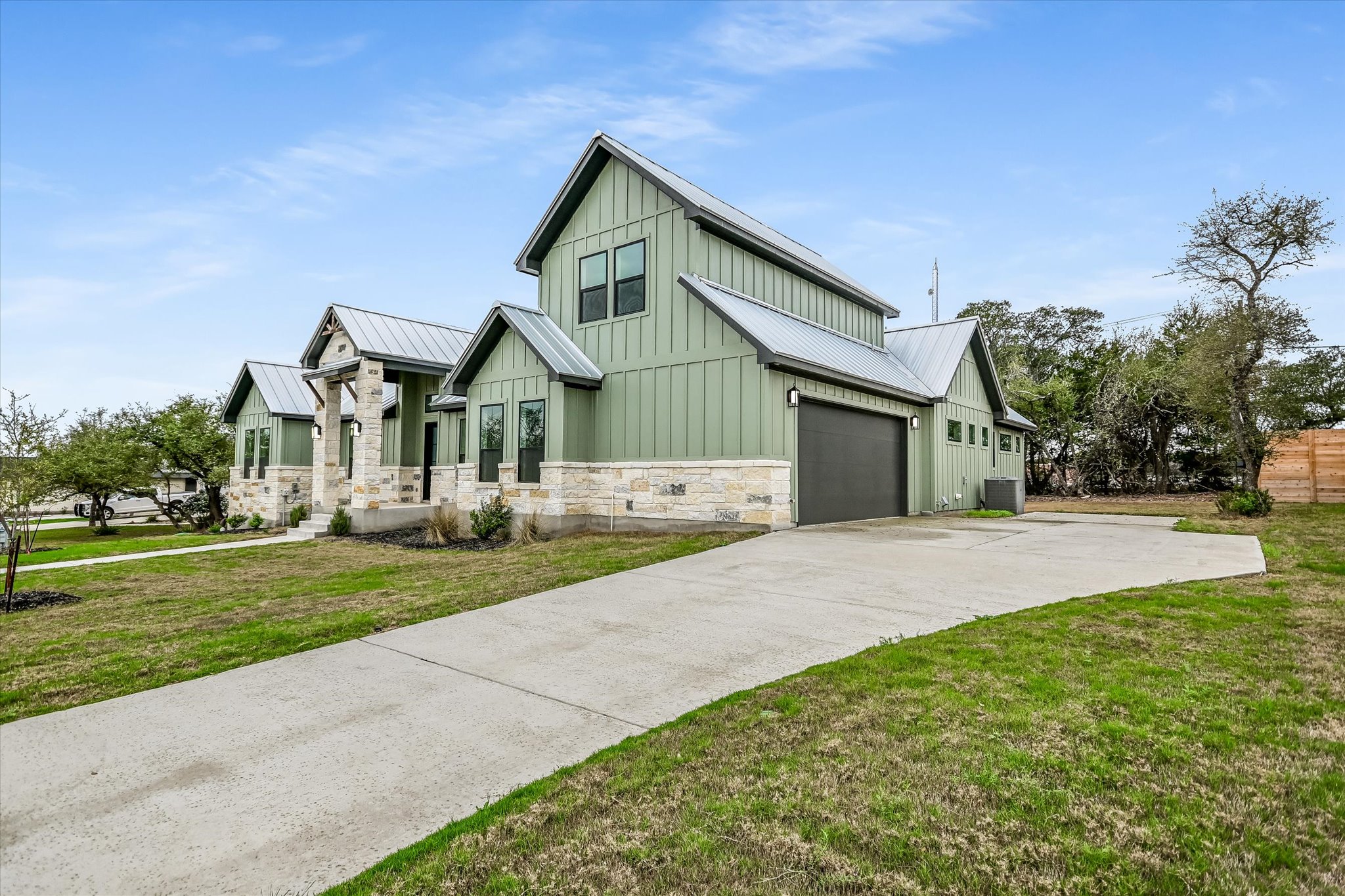 32 Peace Pipe Wimberley, TX 78676 - Photo 2 of 20 Modern farmhouse style home featuring board and batten siding, stone siding, driveway, a front lawn, and a standing seam roof