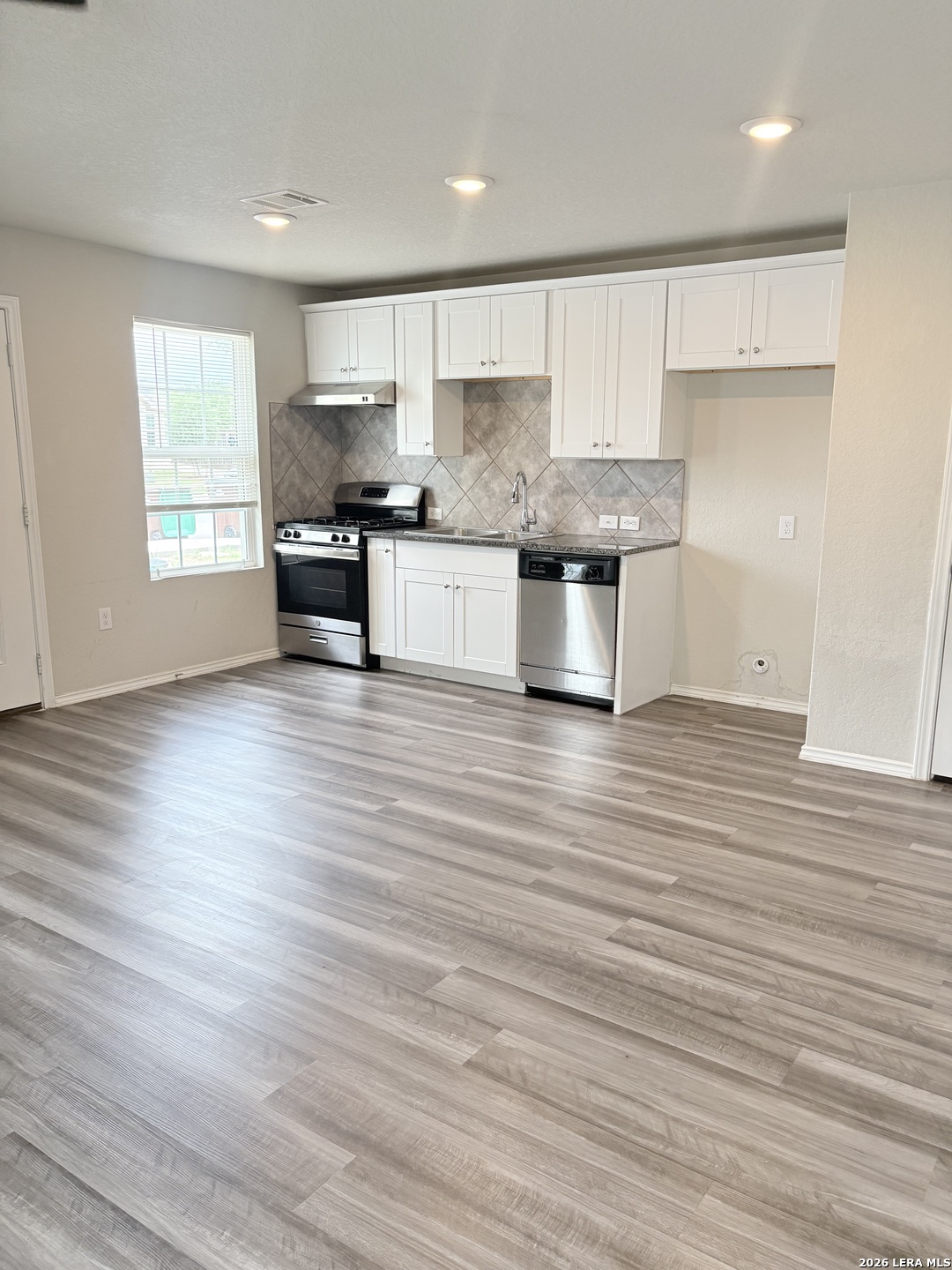 7022 Sunspot Converse, TX 78109 - Photo 4 of 18 a kitchen with granite countertop wooden floors stainless steel appliances and cabinets