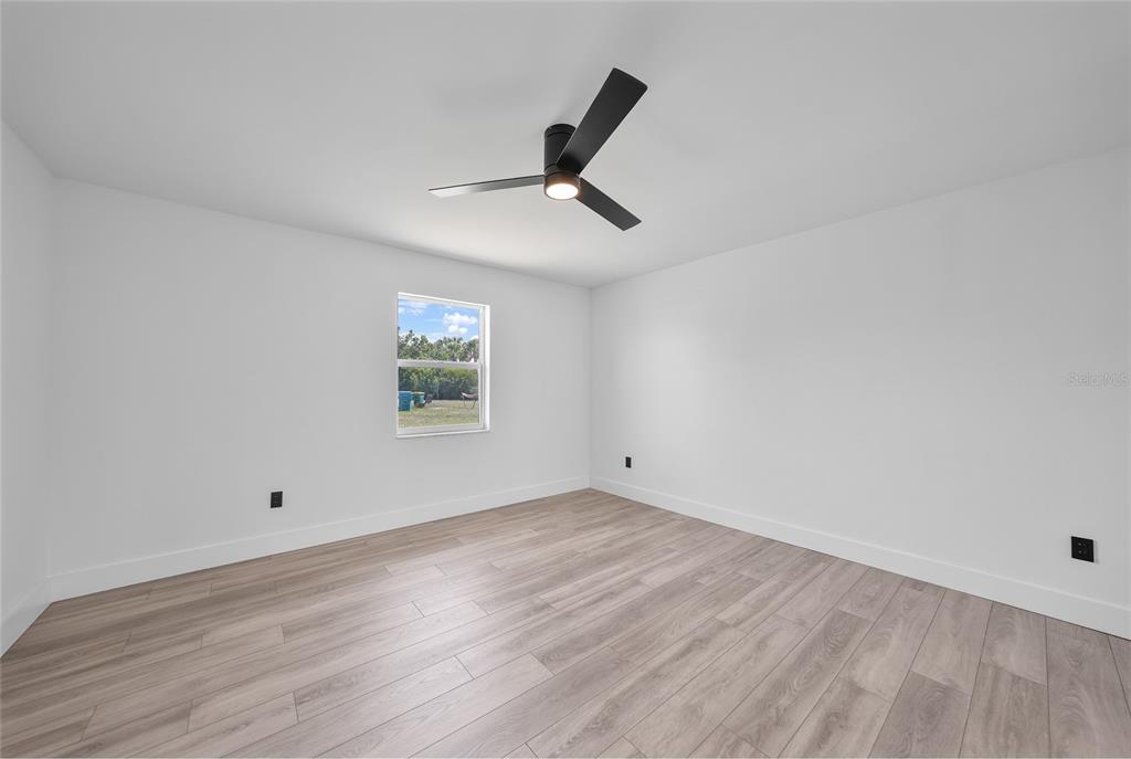 2166 Beacon Drive Port Charlotte, FL 33952 - Photo 16 of 36 a view of empty room with wooden floor and fan