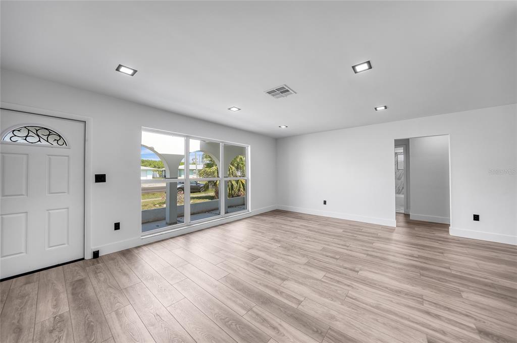 2166 Beacon Drive Port Charlotte, FL 33952 - Photo 4 of 36 a view of an empty room with wooden floor and a window