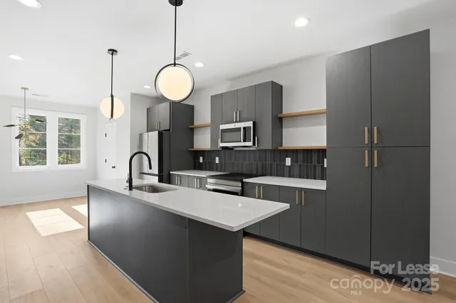 a kitchen with stainless steel appliances granite countertop a sink a stove and a wooden floors