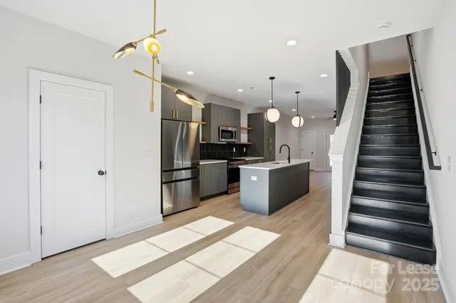 a kitchen with stainless steel appliances kitchen island granite countertop a refrigerator and a sink