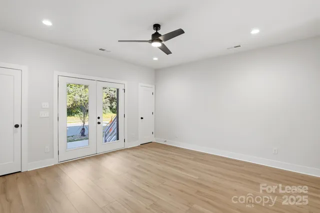 a view of an empty room with a window and wooden floor