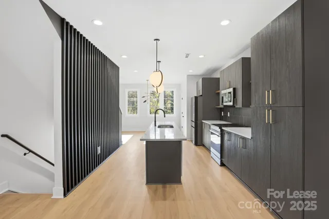 a kitchen with stainless steel appliances kitchen island granite countertop wooden floor a refrigerator and a sink