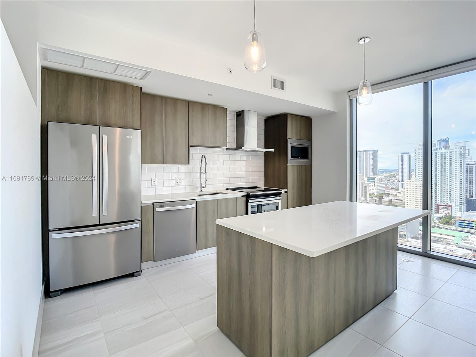 340 Southeast 3rd Street, Unit 1802 Miami, FL 33131 - Photo 11 of 36 a kitchen with refrigerator cabinets and large window