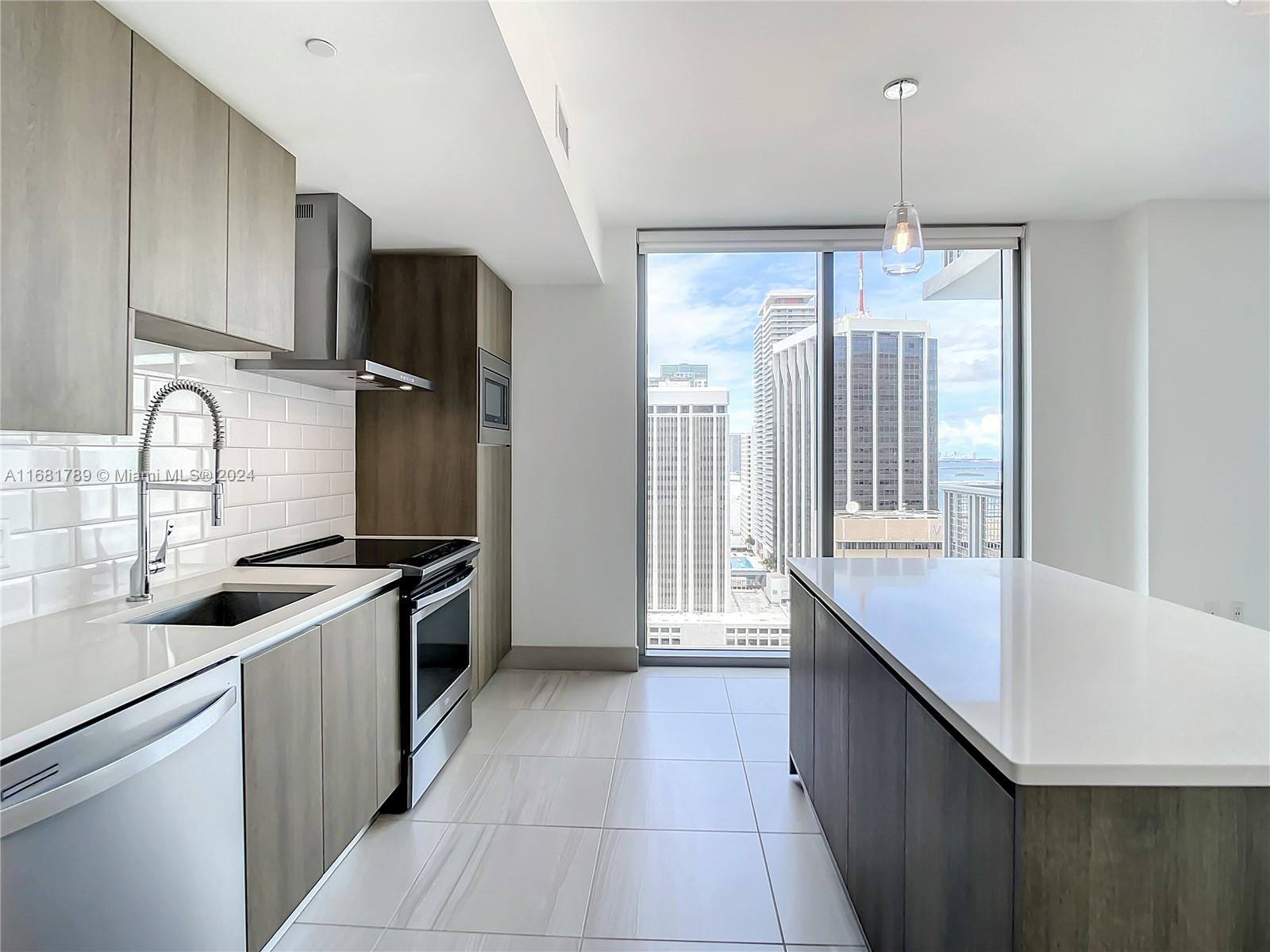 340 Southeast 3rd Street, Unit 1802 Miami, FL 33131 - Photo 12 of 36 a kitchen with granite countertop a stove a sink and a refrigerator