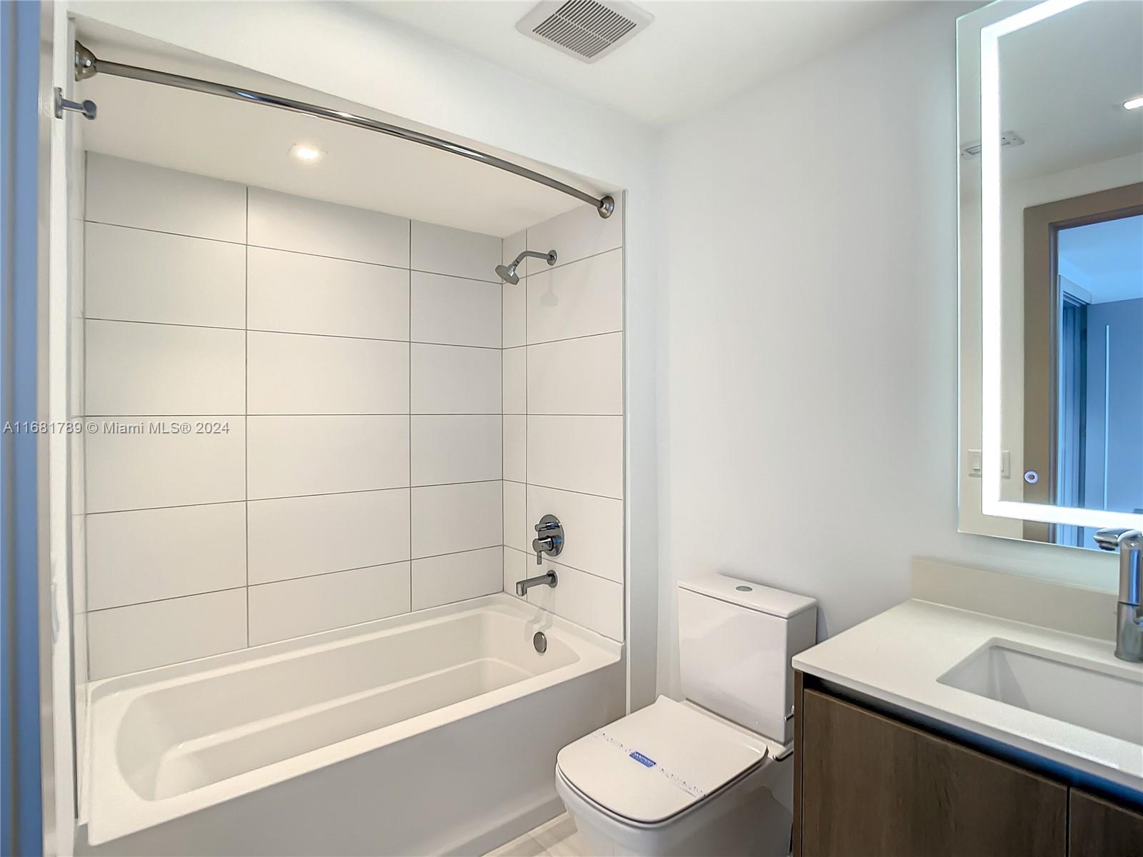 340 Southeast 3rd Street, Unit 1802 Miami, FL 33131 - Photo 20 of 36 a bathroom with a bathtub shower sink vanity and a toilet