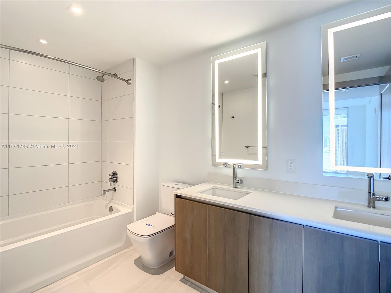 340 Southeast 3rd Street, Unit 1802 Miami, FL 33131 - Photo 26 of 36 a bathroom with a bathtub shower sink vanity and toilet