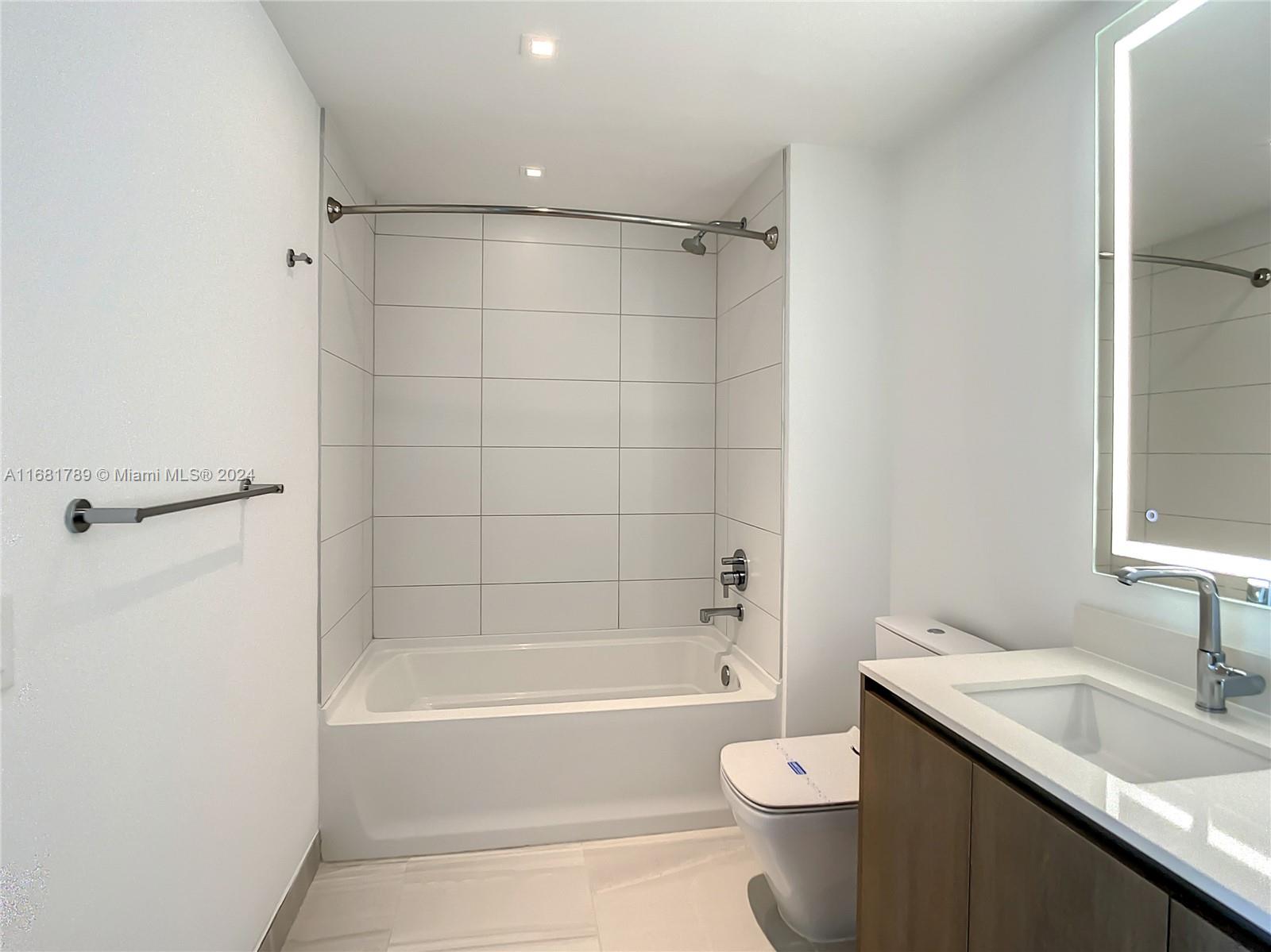 340 Southeast 3rd Street, Unit 1802 Miami, FL 33131 - Photo 27 of 36 a bathroom with a bathtub shower sink vanity and toilet