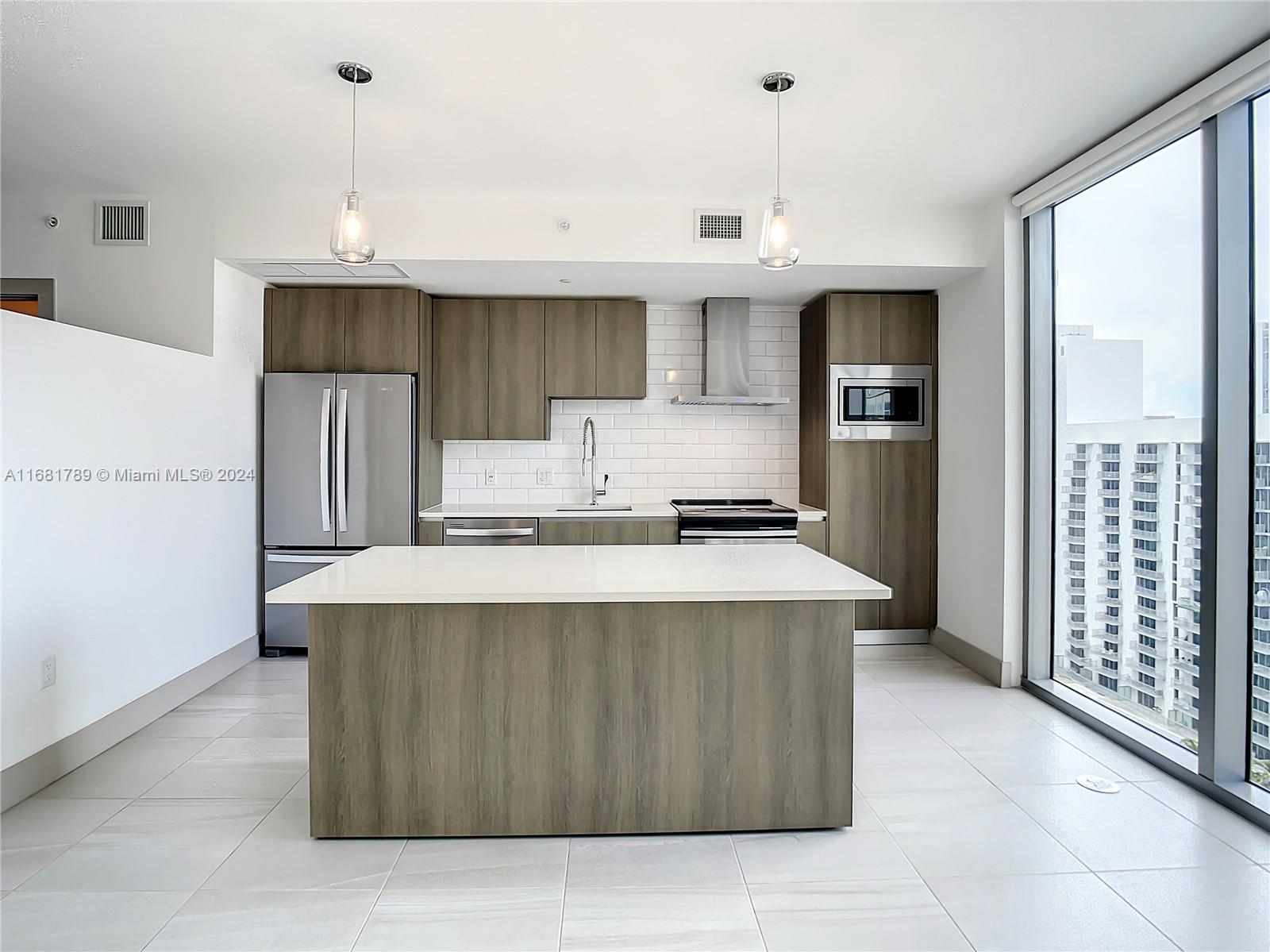 340 Southeast 3rd Street, Unit 1802 Miami, FL 33131 - Photo 8 of 36 a kitchen with kitchen island a counter top a stove a refrigerator and a cabinets