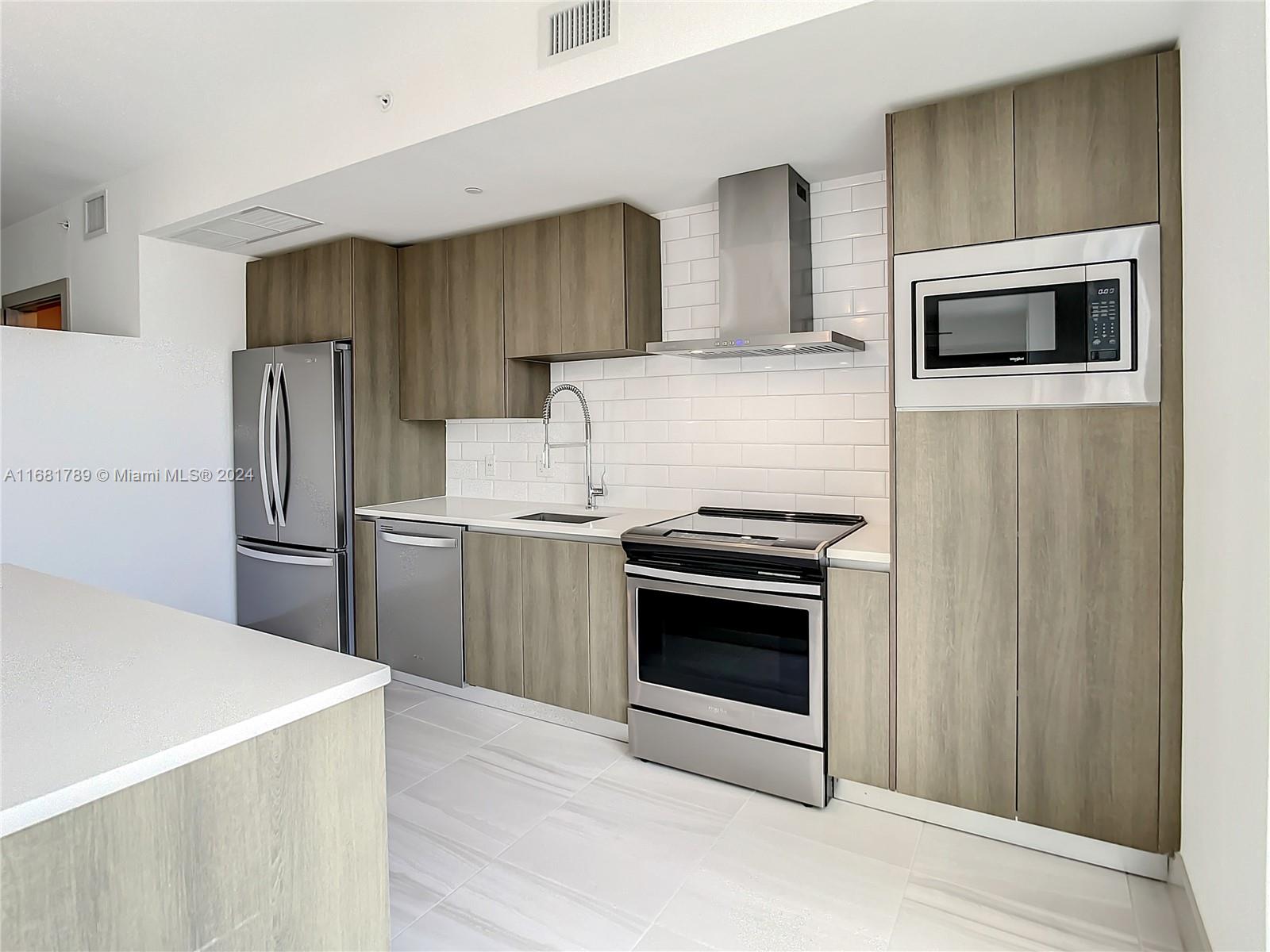 340 Southeast 3rd Street, Unit 1802 Miami, FL 33131 - Photo 9 of 36 a kitchen with stainless steel appliances wooden cabinets and stove