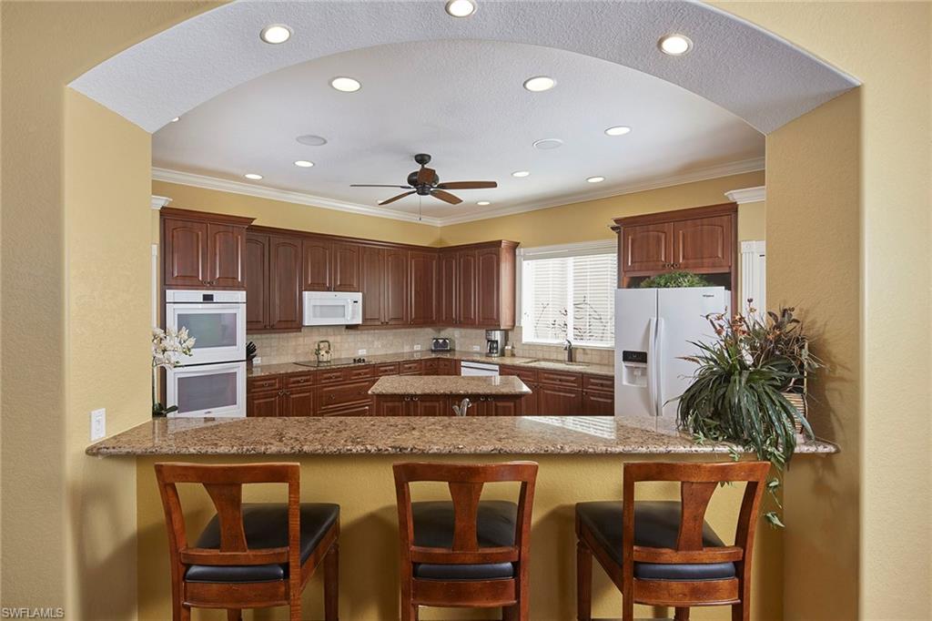 377 Mallory Court Naples, FL 34110 - Photo 11 of 29 a kitchen with granite countertop kitchen island a table and chairs in it