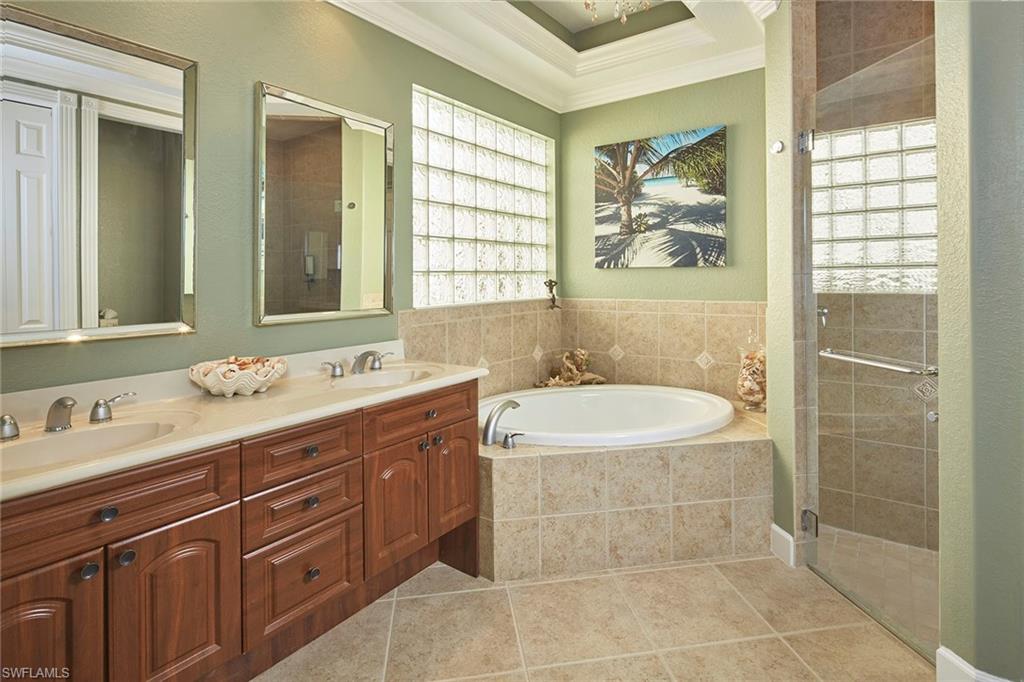 377 Mallory Court Naples, FL 34110 - Photo 13 of 29 a spacious bathroom with a granite countertop sink a large mirror and a bathtub