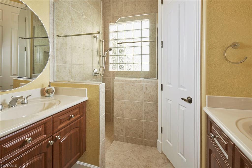 377 Mallory Court Naples, FL 34110 - Photo 15 of 29 a bathroom with a granite countertop sink a mirror and a shower
