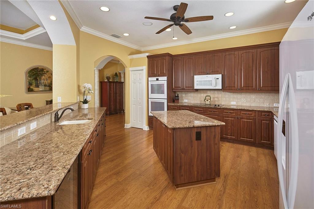377 Mallory Court Naples, FL 34110 - Photo 9 of 29 a kitchen with kitchen island granite countertop wooden cabinets a sink and a stove