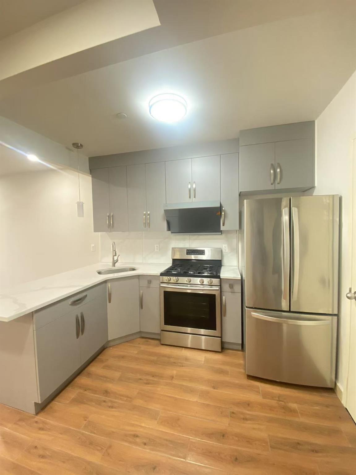 42-22 Crescent Street, Unit 3B Queens, NY 11101 - Photo 2 of 9 a kitchen with wooden cabinets and stainless steel appliances