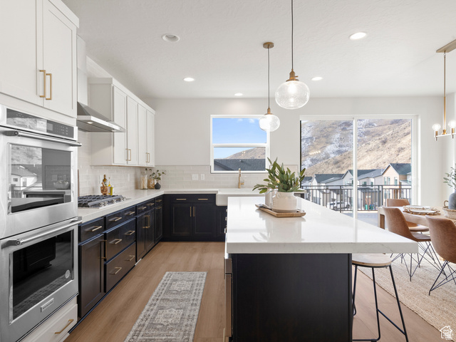 1711 West Canyon Rim Road North Lehi, UT 84048 - Photo 6 of 31 Contemporary kitchen featuring two-tone cabinetry, stainless steel double ovens, a gas range with a stainless steel hood, and a large center island with a white countertop
