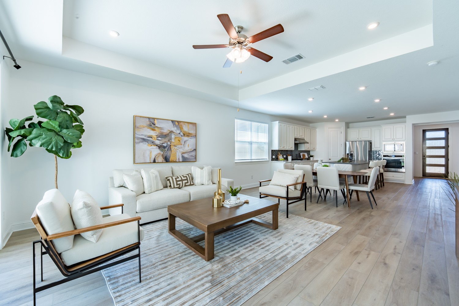 Living room featuring a tray ceiling, recessed lighting, ceiling fan, and light wood finished floors