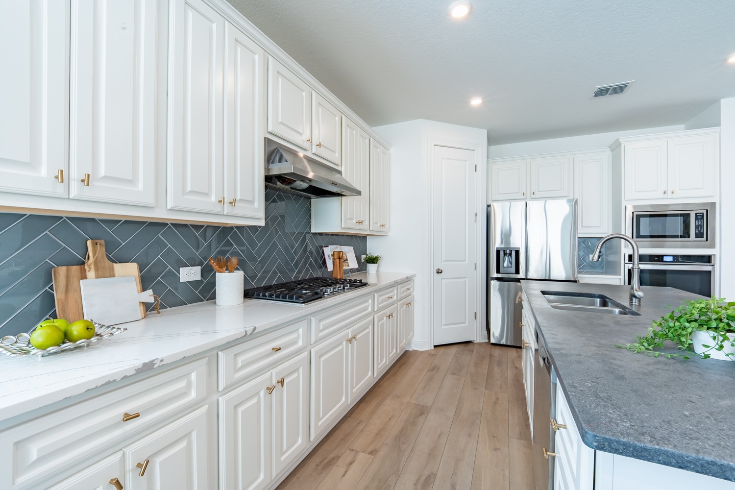 1040 Villa Rialto View Leander, TX 78641 - Photo 12 of 27 Kitchen with white cabinets, light wood-style flooring, stainless steel appliances, light stone counters, and recessed lighting