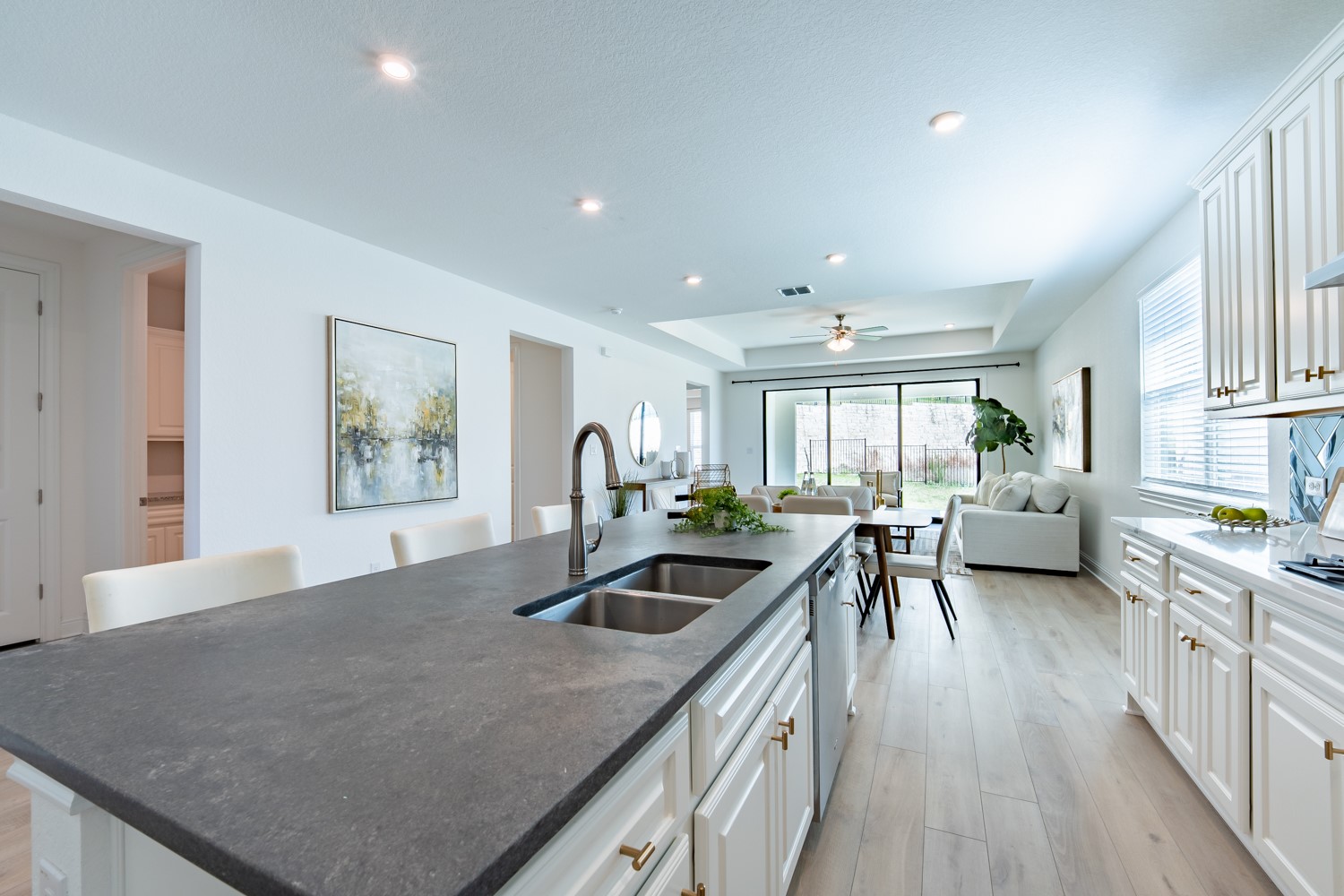 1040 Villa Rialto View Leander, TX 78641 - Photo 14 of 27 Kitchen with a tray ceiling, a center island with sink, white cabinetry, light wood-style floors, and a ceiling fan