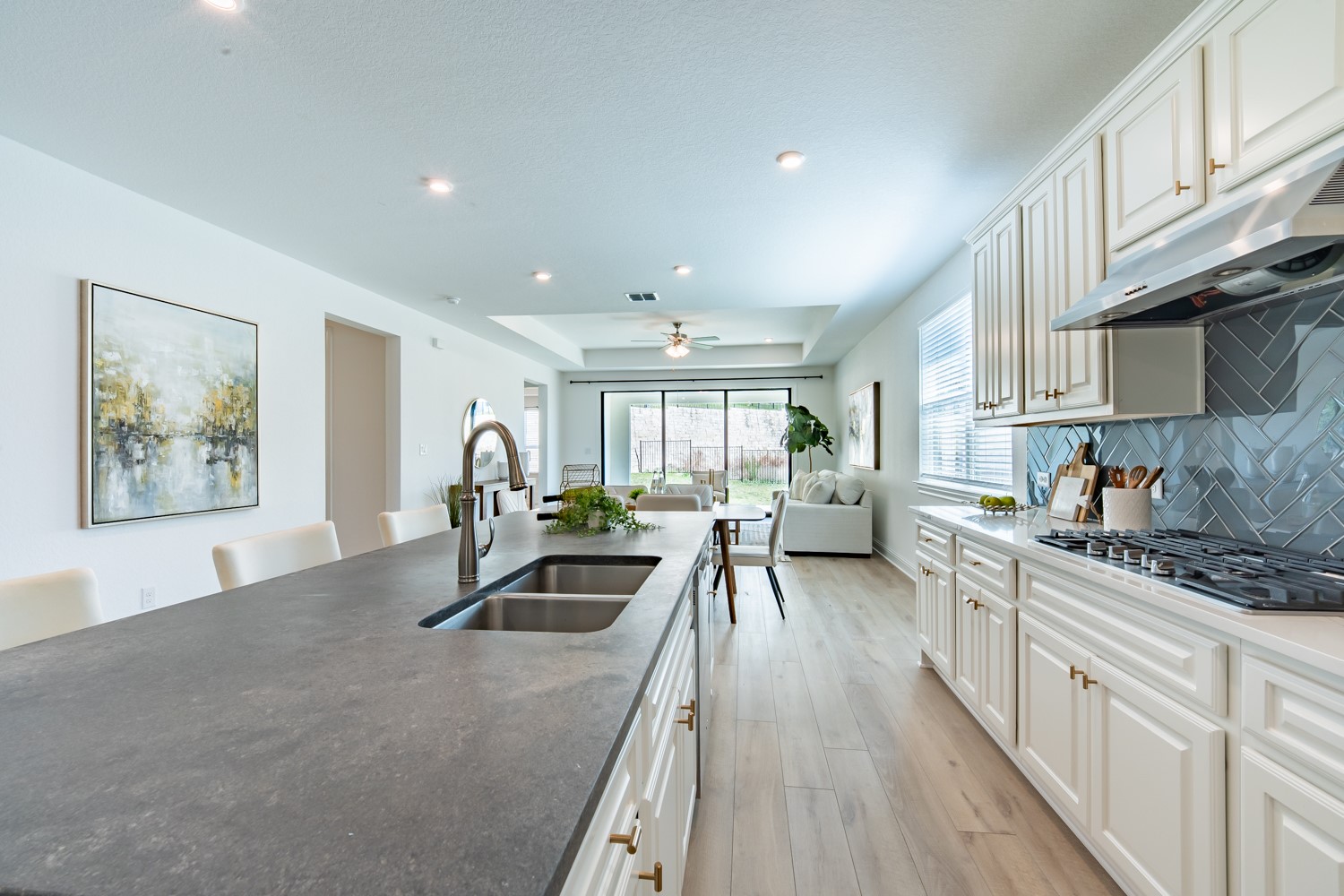1040 Villa Rialto View Leander, TX 78641 - Photo 7 of 27 Kitchen featuring a tray ceiling, white cabinetry, a ceiling fan, light wood-type flooring, and stainless steel gas cooktop