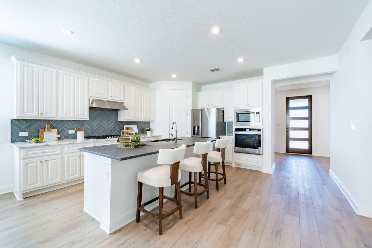 1040 Villa Rialto View Leander, TX 78641 - Photo 9 of 27 Kitchen with a breakfast bar, white cabinetry, an island with sink, stainless steel appliances, and light wood-style flooring