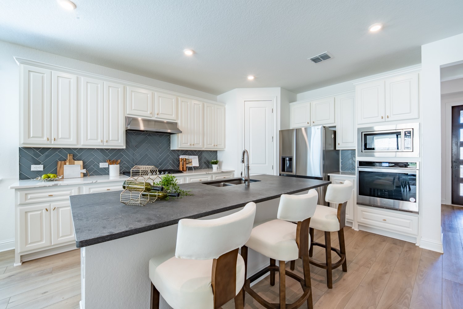 1040 Villa Rialto View Leander, TX 78641 - Photo 10 of 27 Kitchen featuring light wood-type flooring, a kitchen bar, stainless steel appliances, a center island with sink, and white cabinetry