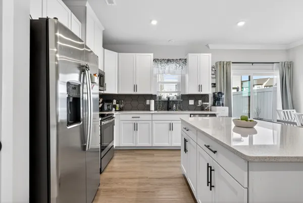 a kitchen with stainless steel appliances kitchen island a table chairs sink and cabinets