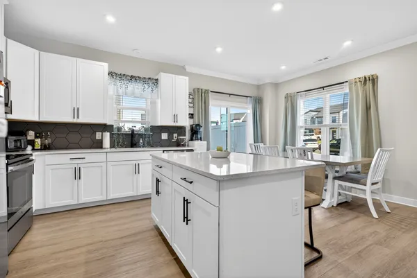 a kitchen with stainless steel appliances granite countertop a refrigerator a stove top oven a sink dishwasher and white cabinets with wooden floor