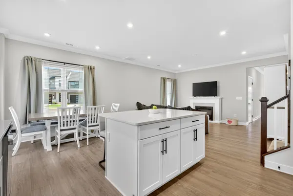 a kitchen with stainless steel appliances granite countertop a refrigerator a stove a sink a dining table and chairs